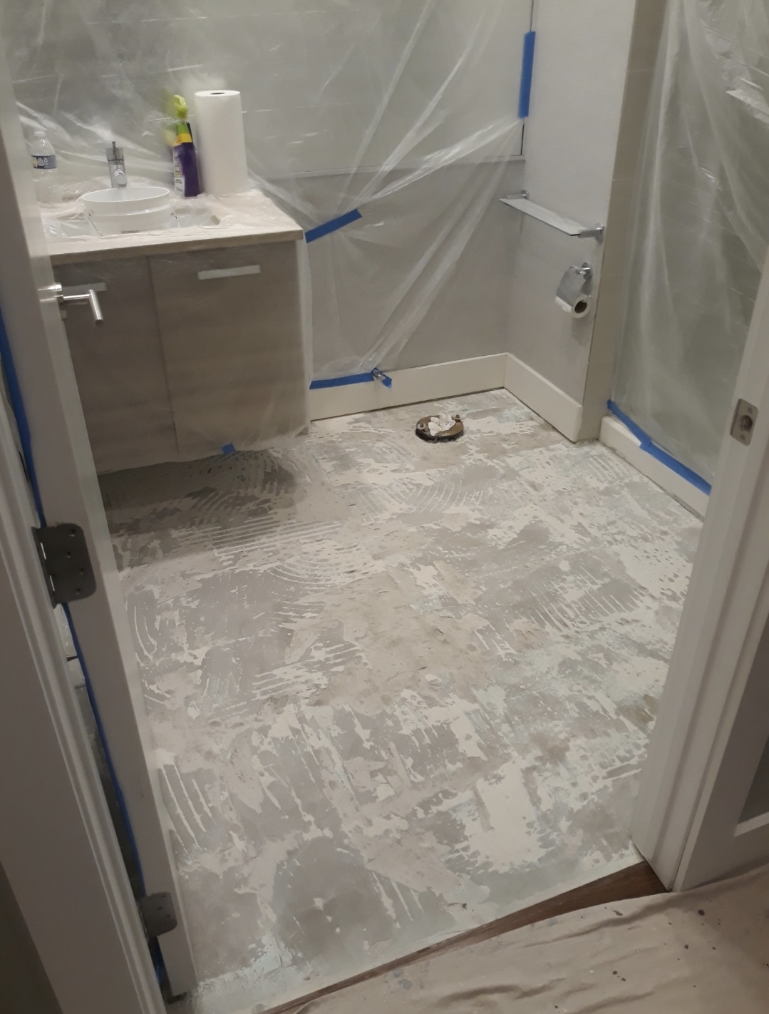 Bathroom mid-renovation, subfloor exposed and protected